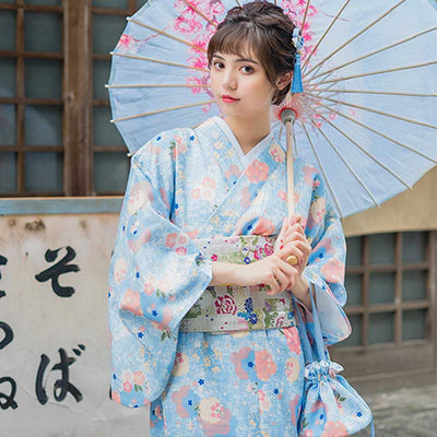 Kimono tradicional japonés con estampado floral, la mujer sostiene con elegancia un wagasa mostrando los intrincados patrones