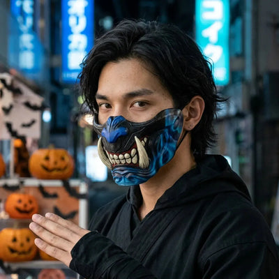 Media máscara oni negra y azul con colmillos de marfil, usada de noche para Halloween con el neón azul de Tokio de fondo