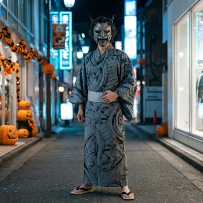 Mascara de oni gris de Halloween llevada de cuerpo entero con un kimono gris con estampado de pincelada en una calle vacia de Tokio de noche
