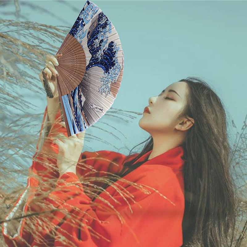 Mujer sosteniendo un abanico japonés con el estampado de la Gran Ola de Kanagawa