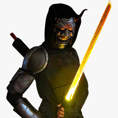 Un hombre vestido con oni ropa ninja, con el rostro oculto por la máscara japonesa de oni. Es una pieza artesanal, con diseños detallados pintados y esculpidos a mano, con cuernos y dientes afilados que dan vida al folclore japonés. El hombre sostiene una espada katana iluminada.