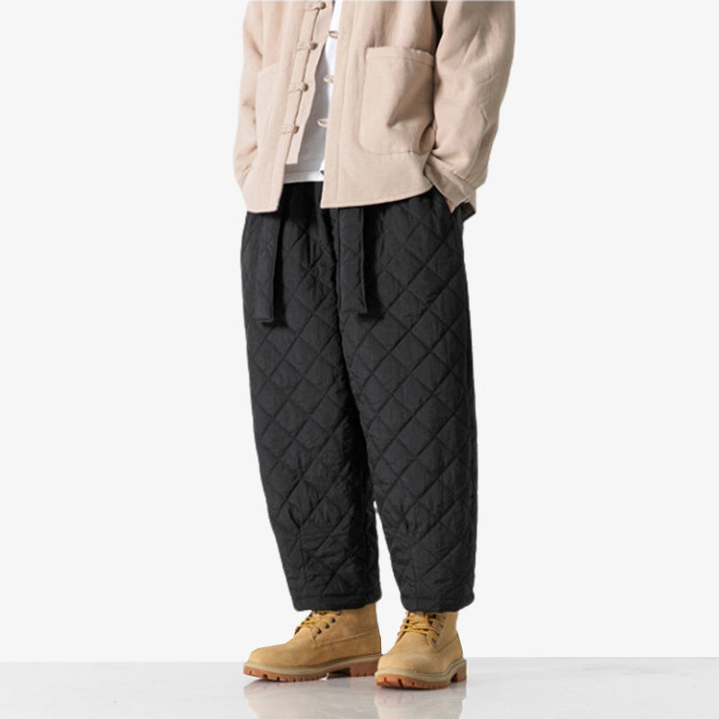 Hombre con pantalón cargo japonés negro, chaqueta beige y botas de montaña