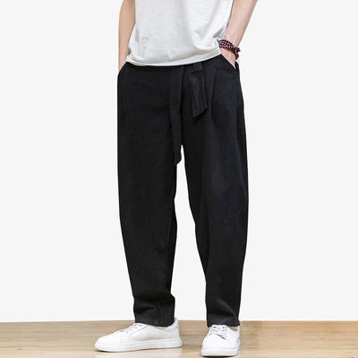 Este traje de pantalones grandes japón​ se abrocha con un cinturón oni. El hombre está de pie, con zapatos blancos bajos y una pulsera de perlas.