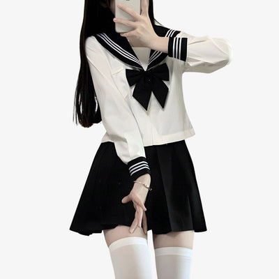 Una niña viste un uniforme sailor fuku cosplay con falda negra japonesa, moño negro japonés y camisa blanca japonesa de estudiante.