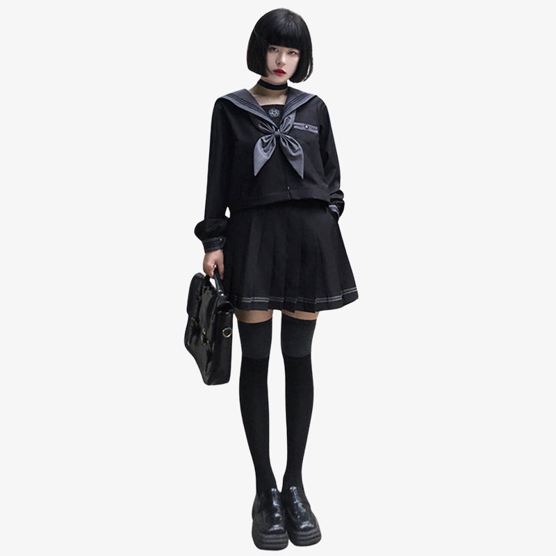 Chica japonesa con uniforme sailor fuku negro de colegiala japonesa. La mujer lleva una falda negra, calcetines largos japoneses y sostiene un bolso negro japonés en las manos.