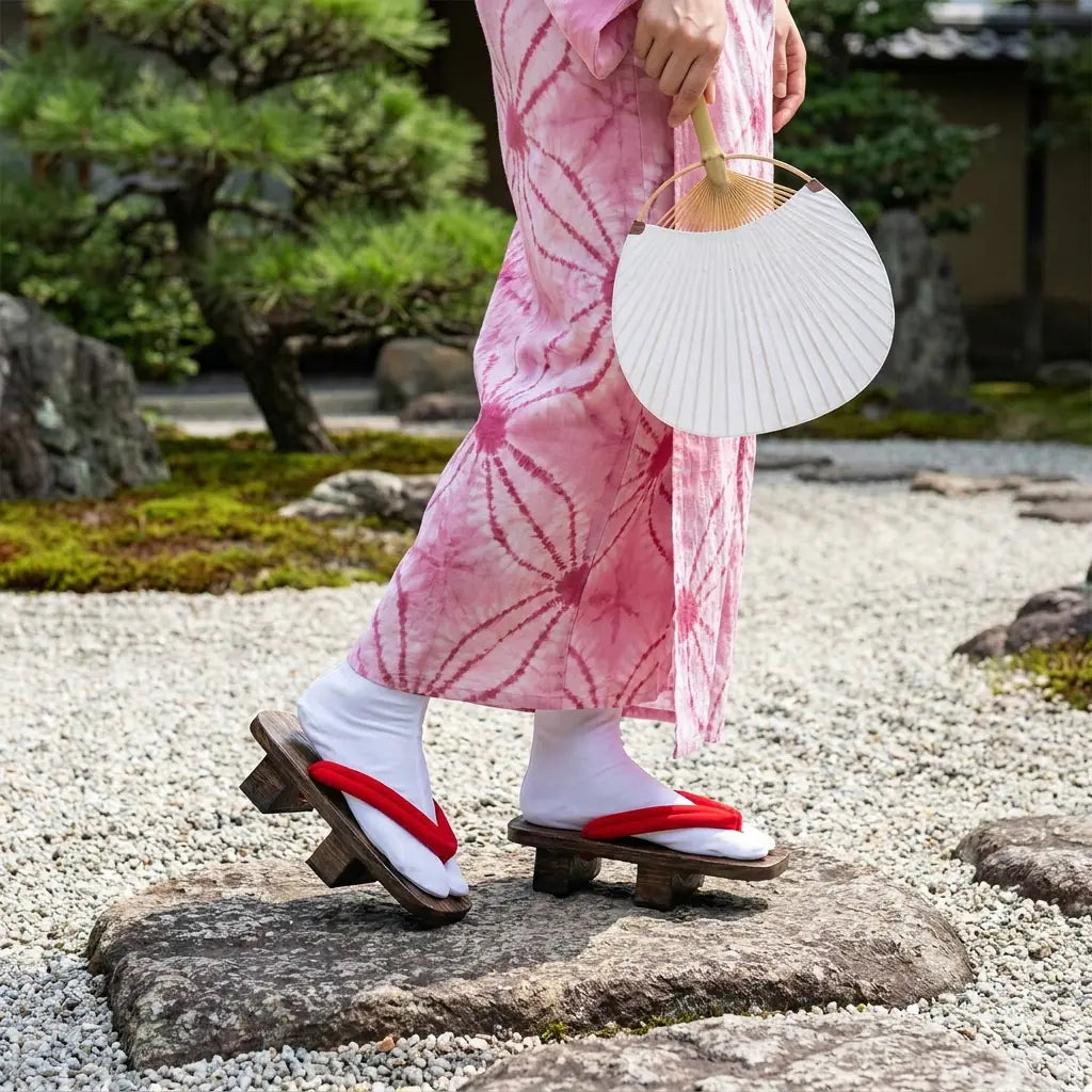 Zapatos geta hombre combinados con un kimono rosa en un jardín japonés