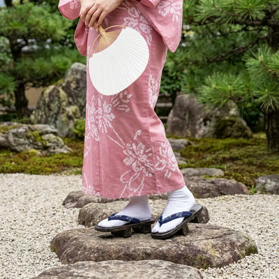 Sandalias geta hanao marino combinadas con un kimono rosa en un jardín japonés