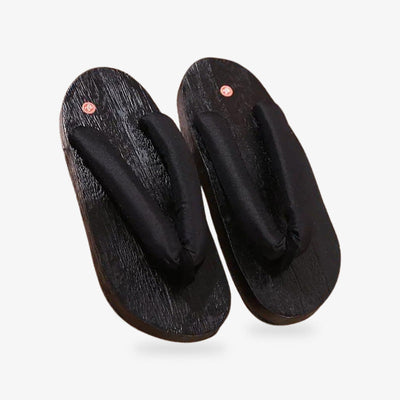 Sandalias geta japonesas de madera negra con correa blanca, estilo tradicional y práctico