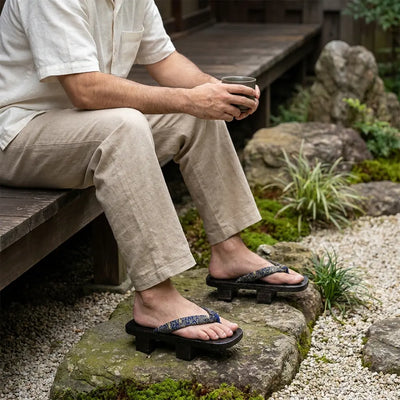 Sandalias geta con calcetines tabi blancos llevadas por un hombre sentado en un jardín japonés