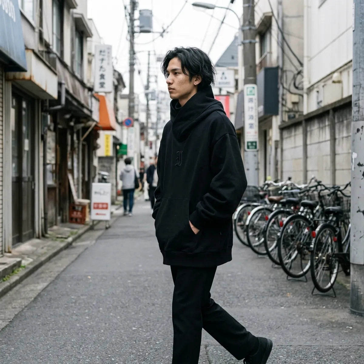 Sudadera oversized negra para hombre, con hombros caídos y mangas anchas captada al caminar por Harajuku