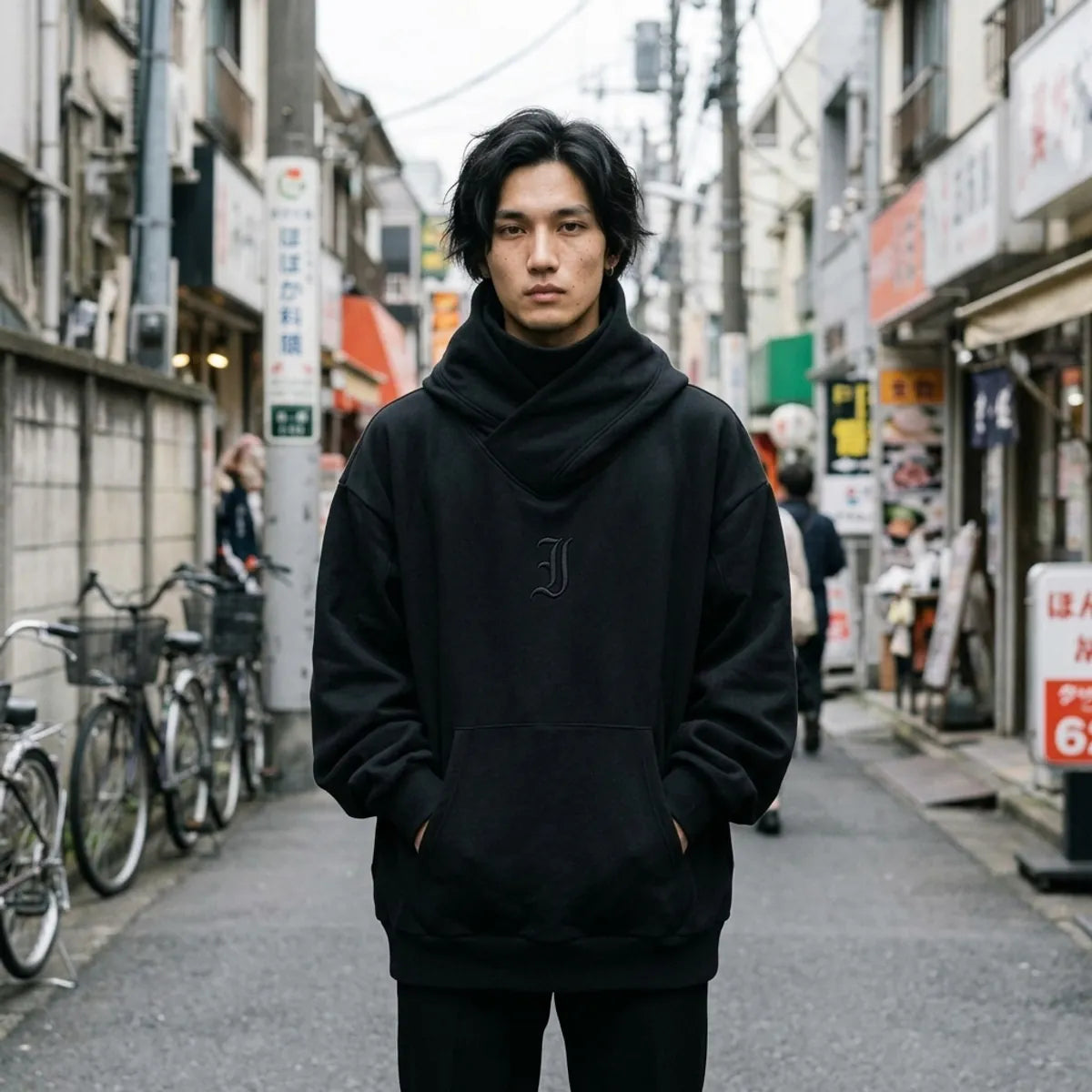 Sudadera Harajuku negra con cuello tipo chimenea cruzado, llevada oversized con las manos en el bolsillo canguro