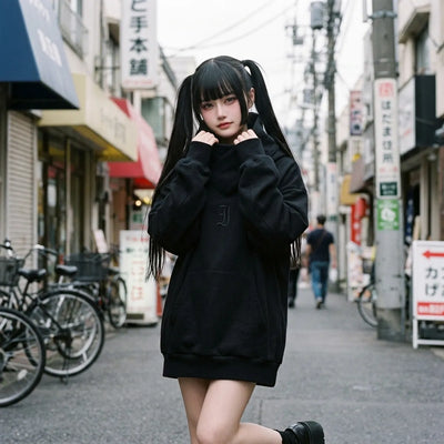 Sudadera oversized negra llevada por una mujer en Harajuku, con el cuello tipo chimenea envolviendo el cuello
