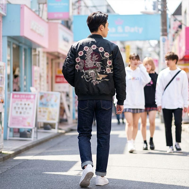Hombre con una chaqueta sukajan negra Raijin con diseños florales caminando por la calle