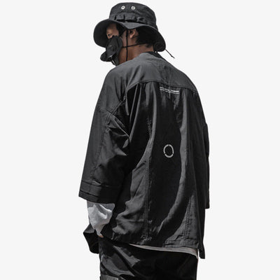Un hombre japonés lleva un kimono negro de ropa techwear fashion. El tejido es impermeable.